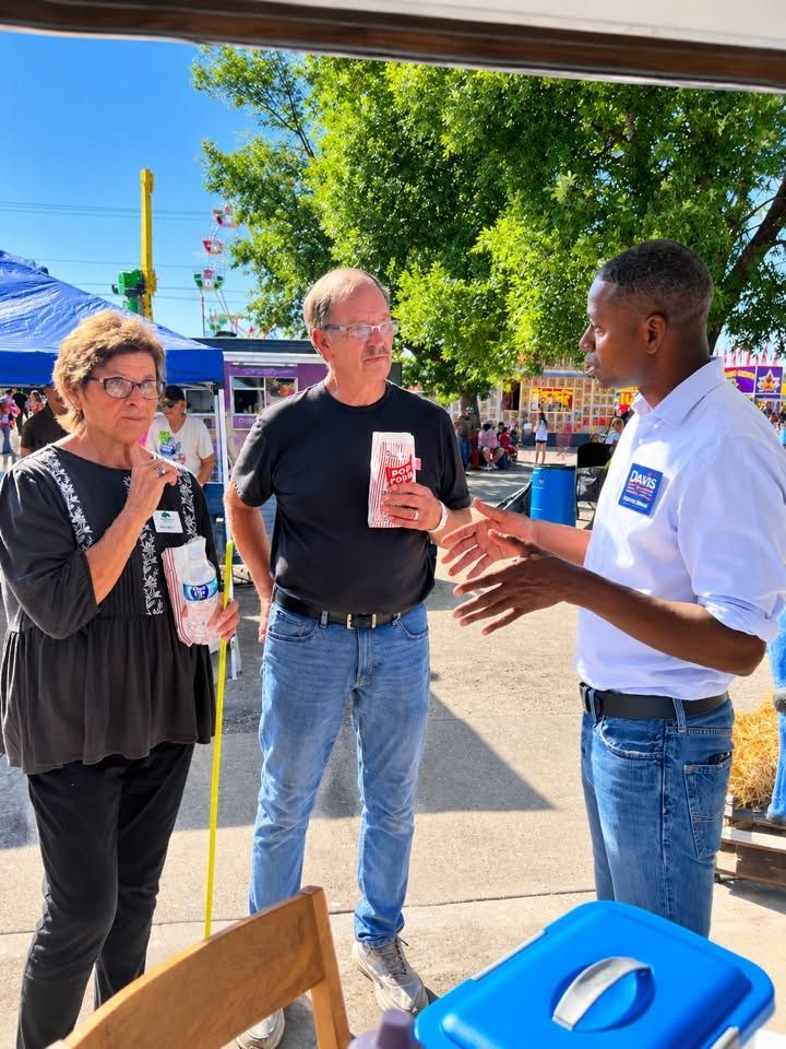 Terrence Davis talking with two voters at a county fair