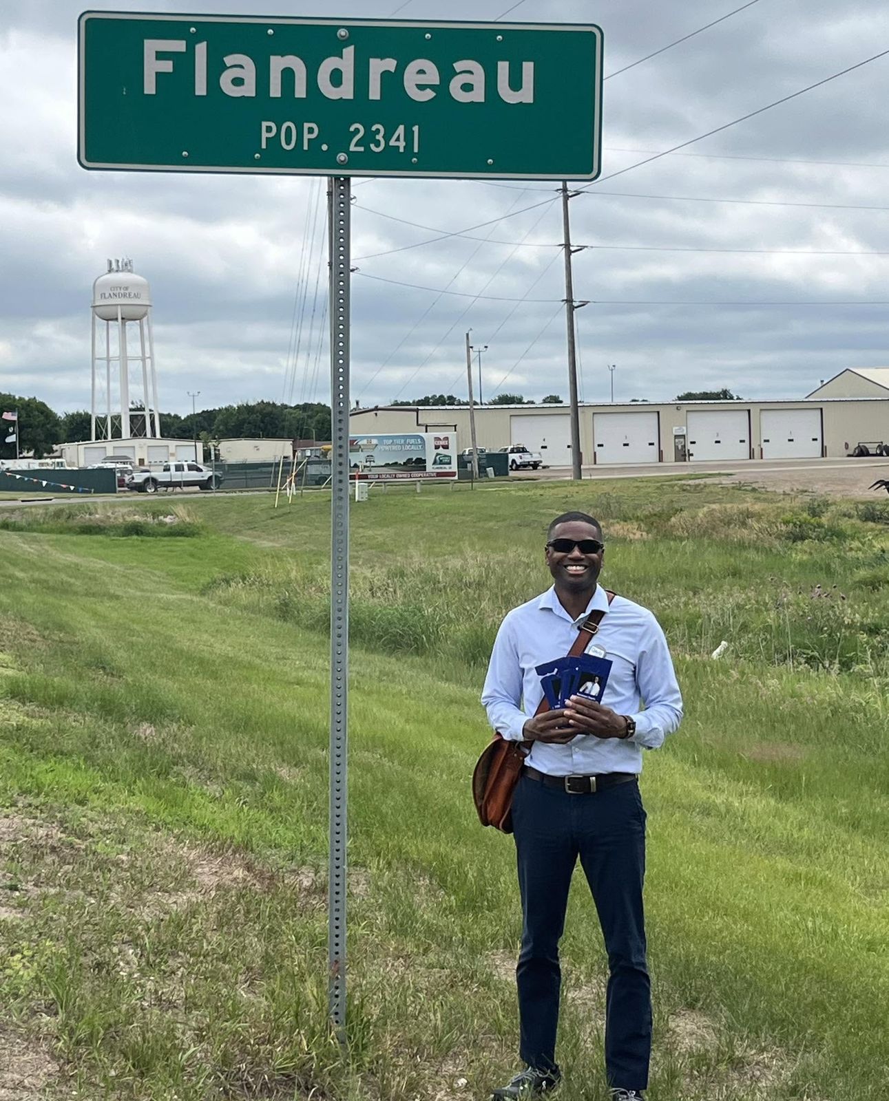 Terrence Davis holding campaign cards beneath the Flandreau town sign